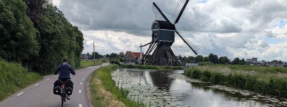 Woman cycling on an e bike past a Dutch windmill on holiday